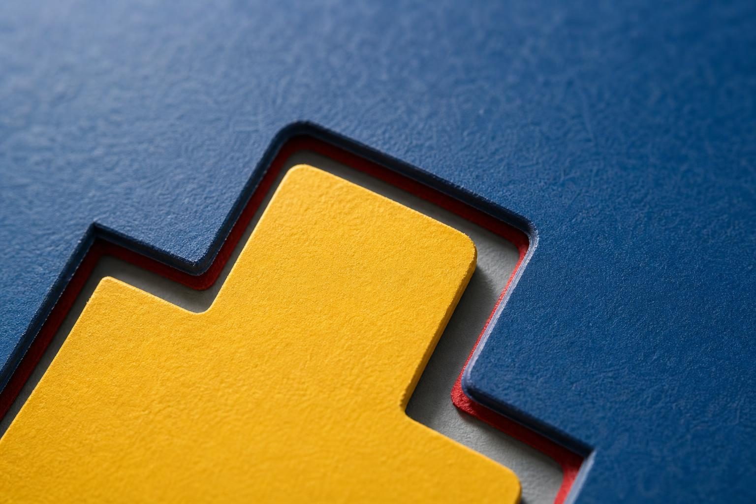 A close-up cut-paper tab fits into a slot, with layered colored edges and strong shadows.