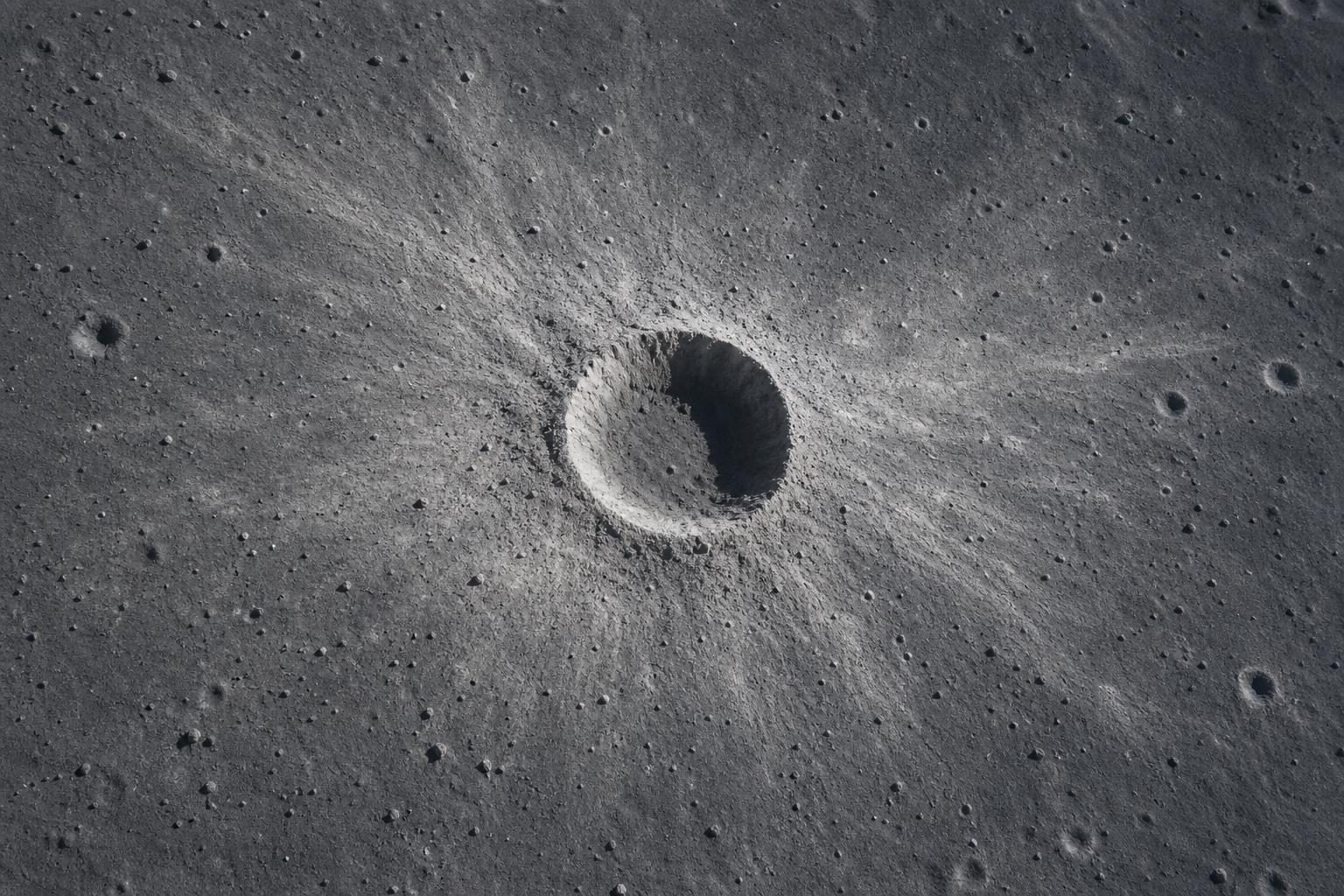 A fresh round crater sits in dusty gray ground on the Moon.